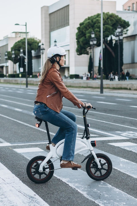 Woman riding a white e-bike across a city crosswalk