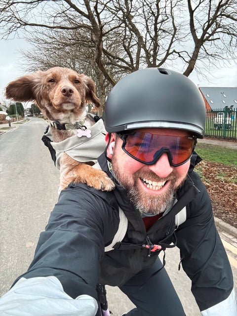 Rider in a Lumos helmet with a small dog in a shoulder carrier